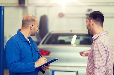 Image showing auto mechanic with clipboard and man at car shop