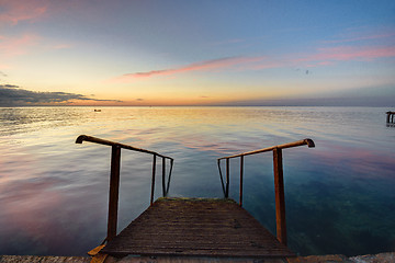 Image showing The old mittal staircase on the pier descends into the sea, against the background of the evening beautiful sunset