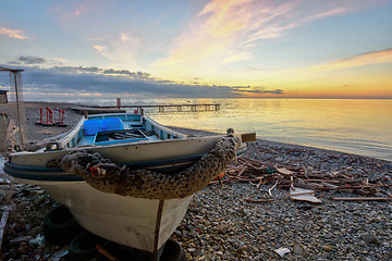 Image showing An old boat on the beach against the backdrop of a beautiful sea sunset