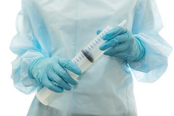 Image showing Hands of medic in sterile gown and gloves hold big syringe, isolated