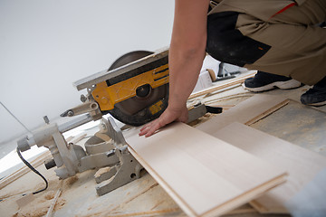 Image showing Man cutting laminate floor plank with electrical circular saw