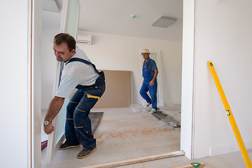 Image showing carpenters installing glass door with a wooden frame