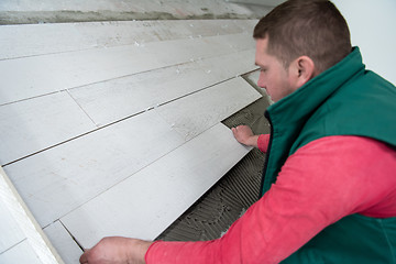 Image showing worker installing the ceramic wood effect tiles on the floor