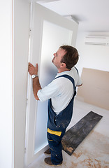 Image showing carpenters installing glass door with a wooden frame