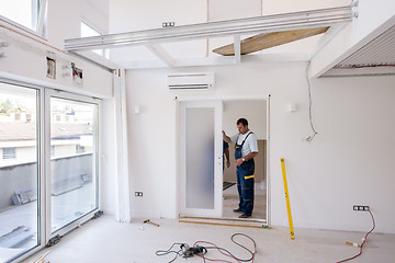 Image showing carpenters installing glass door with a wooden frame