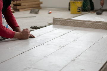 Image showing worker installing the ceramic wood effect tiles on the floor