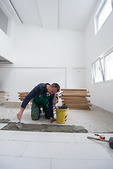 Image showing worker installing the ceramic wood effect tiles on the floor