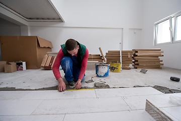 Image showing worker installing the ceramic wood effect tiles on the floor