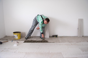 Image showing worker installing the ceramic wood effect tiles on the floor