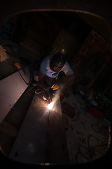 Image showing welder with protective mask welding steel