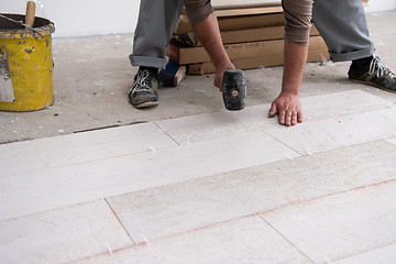 Image showing worker installing the ceramic wood effect tiles on the floor