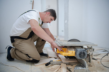 Image showing Man cutting laminate floor plank with electrical circular saw