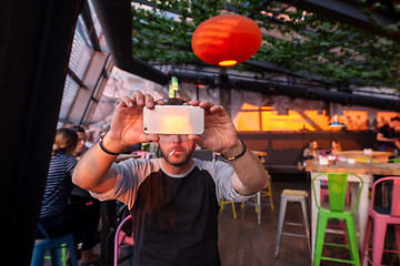 Image showing man taking picture in cafe decorate with hanging plant