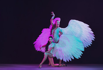 Image showing Young female dancers with angel\'s wings in neon light on black background