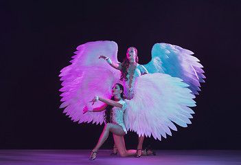 Image showing Young female dancers with angel\'s wings in neon light on black background