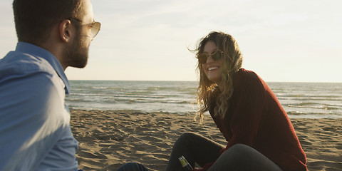 Image showing Loving Young Couple Sitting On The Beach beside Campfire drinkin