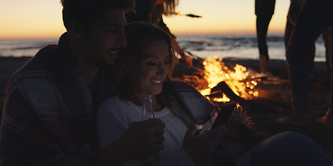 Image showing Couple enjoying bonfire with friends on beach