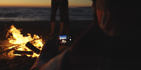 Image showing Couple taking photos beside campfire on beach