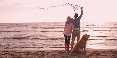 Image showing couple with dog having fun on beach on autmun day