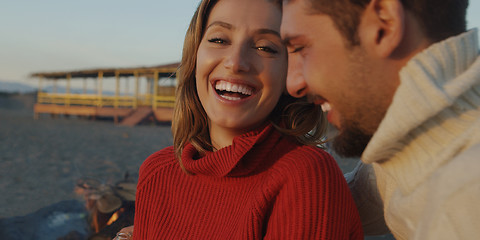 Image showing Loving Young Couple Sitting On The Beach beside Campfire drinkin