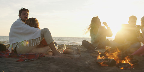 Image showing Loving Young Couple Sitting On The Beach beside Campfire drinkin