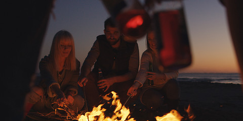 Image showing Young Friends Making A Toast With Beer Around Campfire at beach