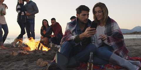 Image showing Couple enjoying bonfire with friends on beach