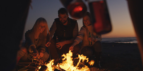 Image showing Young Friends Making A Toast With Beer Around Campfire at beach