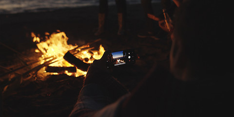 Image showing Couple taking photos beside campfire on beach