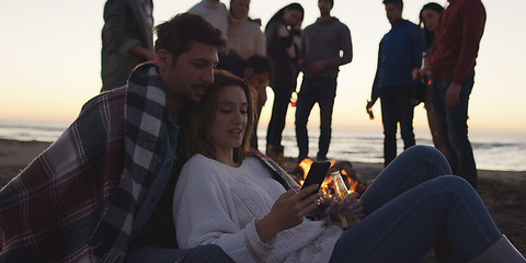 Image showing Couple enjoying bonfire with friends on beach