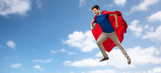 Image showing man in red superhero cape flying over sky