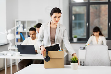 Image showing sad female office worker packing personal stuff