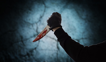 Image showing hand with blood on knife over dark background