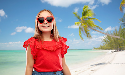 Image showing smiling girl with heart shaped sunglasses on beach