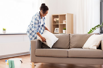 Image showing african american woman arranging sofa cushions