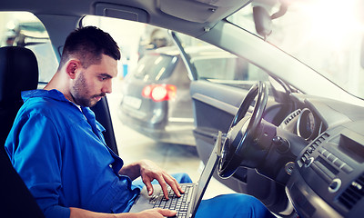 Image showing mechanic man with laptop making car diagnostic