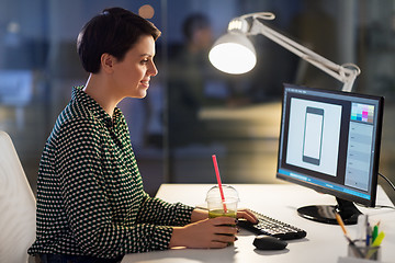 Image showing designer with smoothie at computer at night office