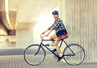 Image showing young hipster man with bag riding fixed gear bike