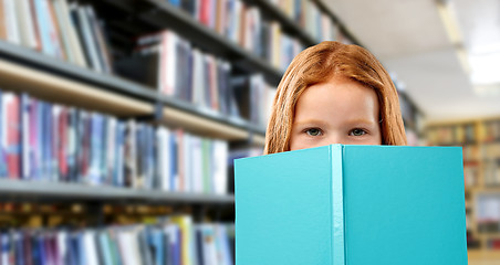 Image showing smiling red haired girl reading book at library