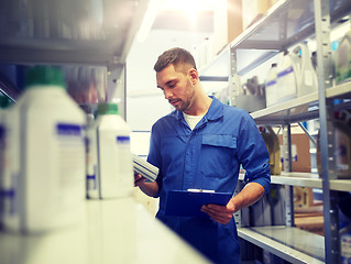 Image showing auto mechanic with oil and clipboard at car shop