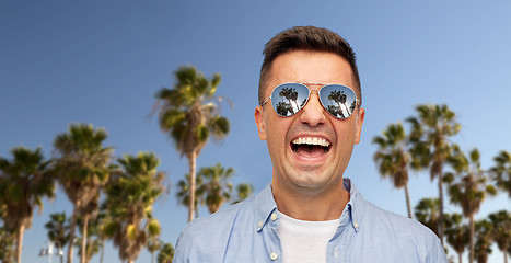 Image showing laughing man in sunglasses over palm trees