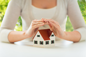 Image showing close up of woman protecting house model by hands