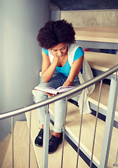 Image showing african student girl reading book on stairs