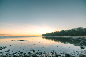 Image showing Lake in the sunrise with rocks on the beach