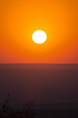 Image showing Large red sunset over silhouettes of hills