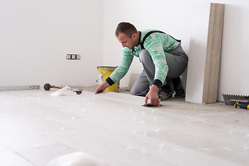 Image showing worker installing the ceramic wood effect tiles on the floor