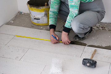 Image showing worker installing the ceramic wood effect tiles on the floor