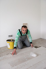 Image showing worker installing the ceramic wood effect tiles on the floor