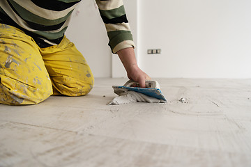 Image showing Tilers filling the space between ceramic wood effect tiles