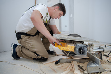 Image showing Man cutting laminate floor plank with electrical circular saw